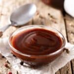 BBQ sauce in a small glass bowl next to a spoon